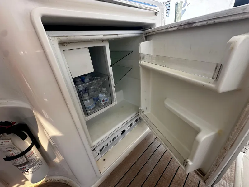 Slide: The Image of Open fridge on 2006 Chris-Craft 43 Roamer yacht, showing stocked beverages and fire extinguisher nearby. - 8