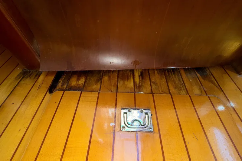 Slide: The Image of Wooden floor of 2006 Chris-Craft Roamer 40 with visible water damage and metal latch. - 37