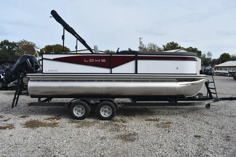 Slide: The Image of 2026 Lowe LS 210 WT pontoon boat on trailer, parked on gravel lot. - 4