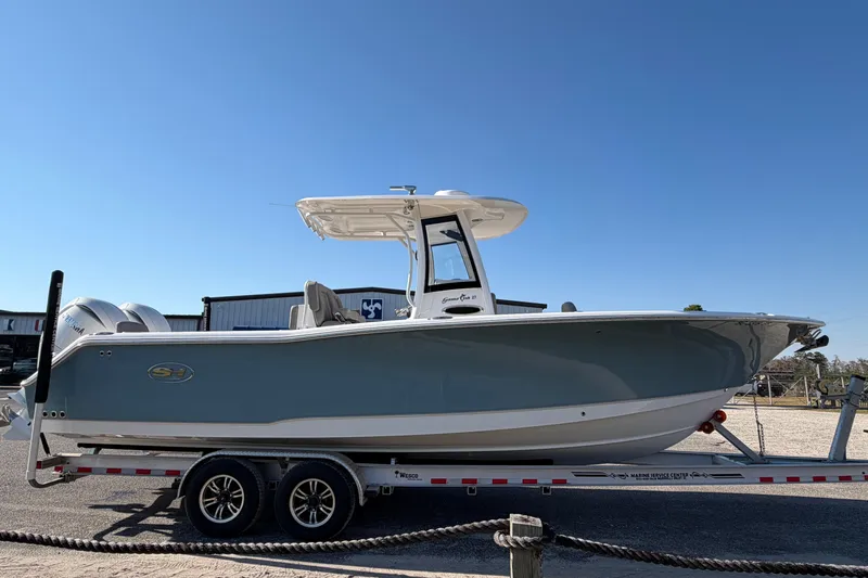 Slide: The Image of 2025 Sea Hunt Gamefish 27 Forward Seating boat on trailer under clear blue sky. - 3
