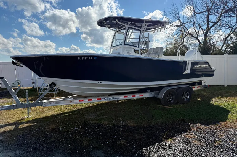 The Image of 2021 Sportsman Heritage 251 Center Console boat on trailer under blue sky. - 1