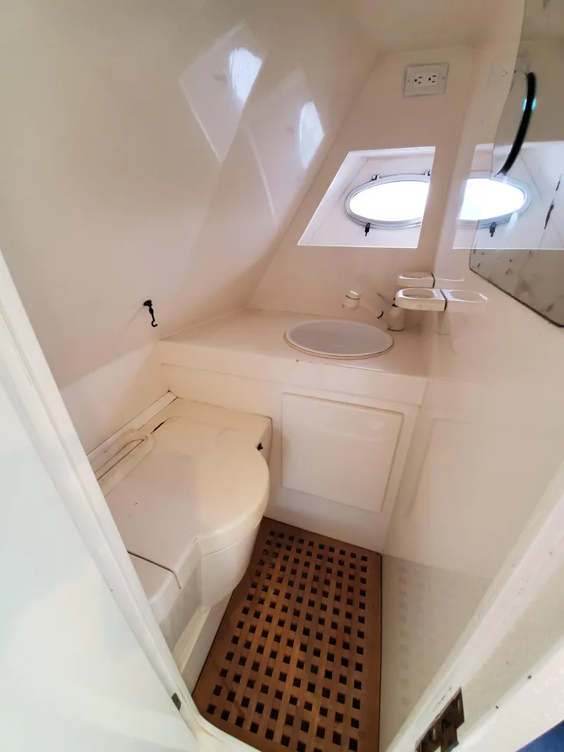 Slide: The Image of Compact bathroom in a 1993 Giorgi 46 boat, featuring a toilet, sink, and porthole windows. - 30