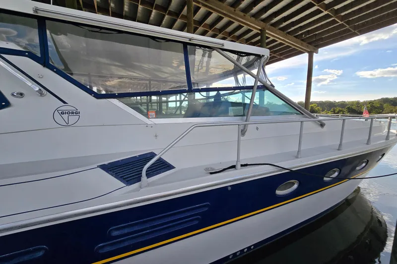 Slide: The Image of 1993 Giorgi 46 boat docked under a covered structure, featuring sleek design and blue accents. - 83