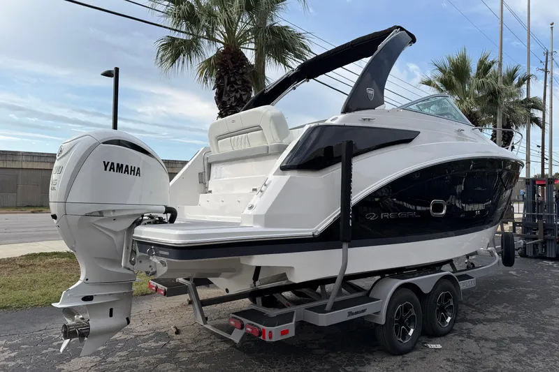 Slide: The Image of 2026 Regal 26 XO boat with Yamaha outboard engine on a trailer, parked near palm trees. - 5