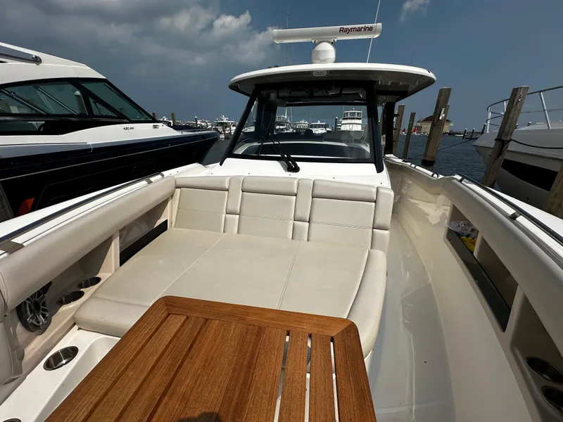 Slide: The Image of 2022 Boston Whaler 350 Realm boat with spacious seating and wooden table, docked at marina. - 25