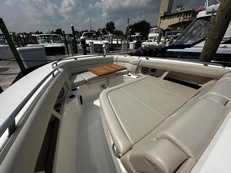 Slide: The Image of 2022 Boston Whaler 350 Realm boat interior with cushioned seating and wooden table. - 26