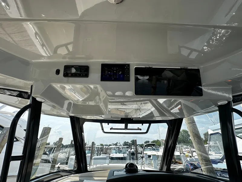 Slide: The Image of 2022 Boston Whaler 350 Realm helm with modern controls and marina view. - 31