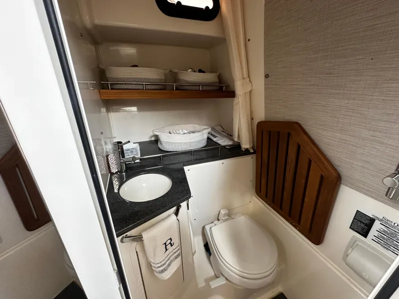 Slide: The Image of 2022 Boston Whaler 350 Realm bathroom with sink, toilet, and storage shelves. - 43