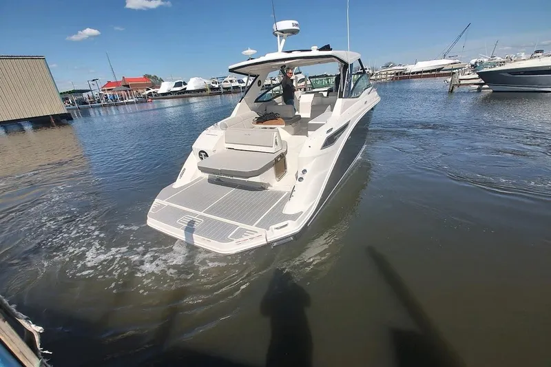 Slide: The Image of 2023 Sea Ray 320 Sundancer yacht docked in a marina under clear blue skies. - 4