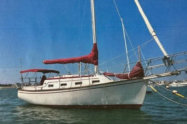 The Image of 1987 Island Packet 27 sailboat with red sails on calm water. - 1