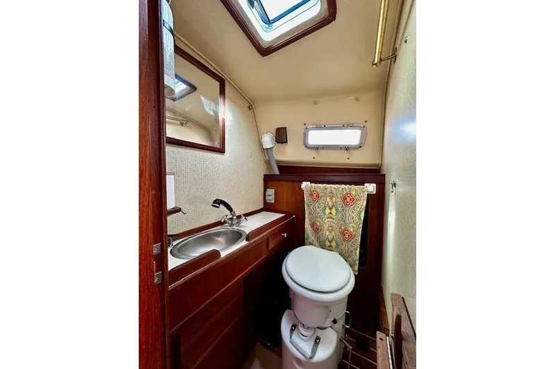 Slide: The Image of 1987 Island Packet 27 sailboat bathroom with sink, toilet, and window. - 10