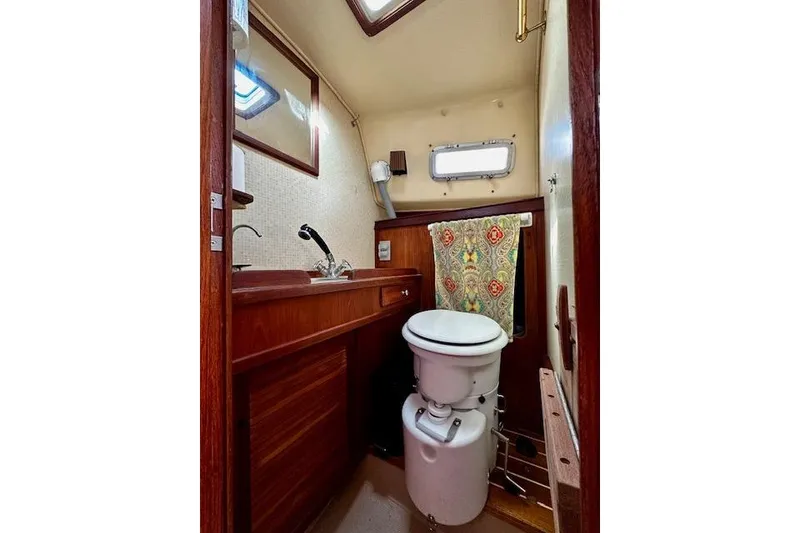 Slide: The Image of 1987 Island Packet 27 sailboat bathroom with wooden cabinetry and compact toilet. - 11