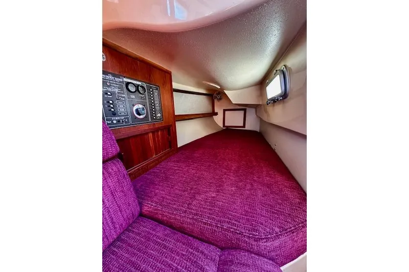 Slide: The Image of Interior of 1987 Island Packet 27 sailboat with purple upholstery and control panel. - 13