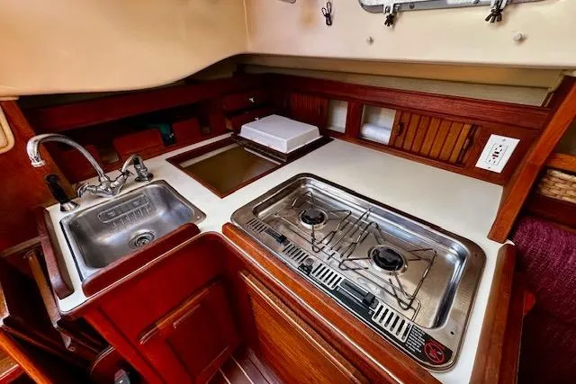 Slide: The Image of 1987 Island Packet 27 yacht kitchen with sink, stove, and wooden cabinetry. - 14