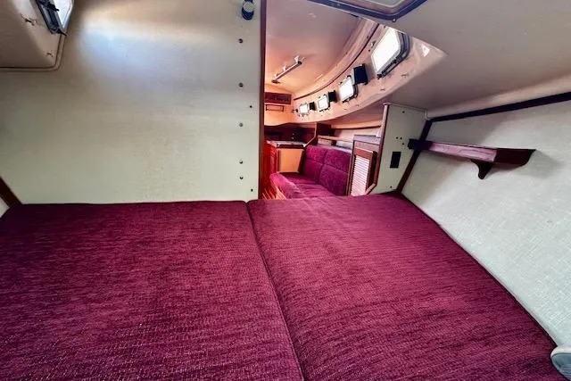 Slide: The Image of Interior of 1987 Island Packet 27 sailboat with burgundy upholstery and wooden accents. - 17