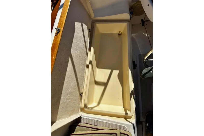 Slide: The Image of 1987 Island Packet 27 sailboat cockpit storage compartment with wooden trim. - 21