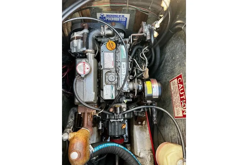 Slide: The Image of 1987 Island Packet 27 engine compartment with visible mechanical components and caution signs. - 22