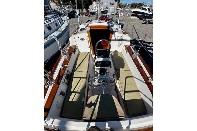 Slide: The Image of 1987 Island Packet 27 sailboat cockpit with cushioned seating and steering wheel. - 3