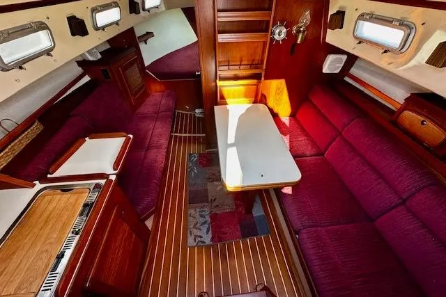 Slide: The Image of Interior of 1987 Island Packet 27 sailboat with red seating and wooden finishes. - 6