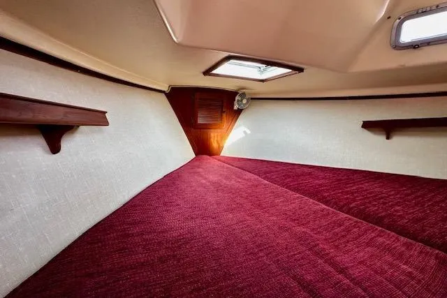 Slide: The Image of Interior cabin of 1987 Island Packet 27 sailboat with red bedding and wooden shelves. - 9
