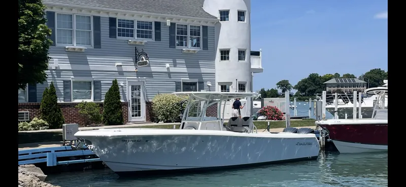 The Image of 2022 Sailfish 290cc boat docked near a waterfront house. - 0