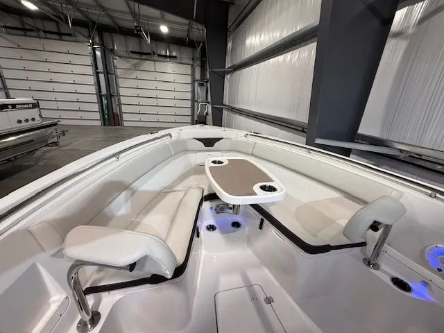 Slide: The Image of 2022 Sailfish 290cc boat interior with seating and table in a spacious garage. - 10