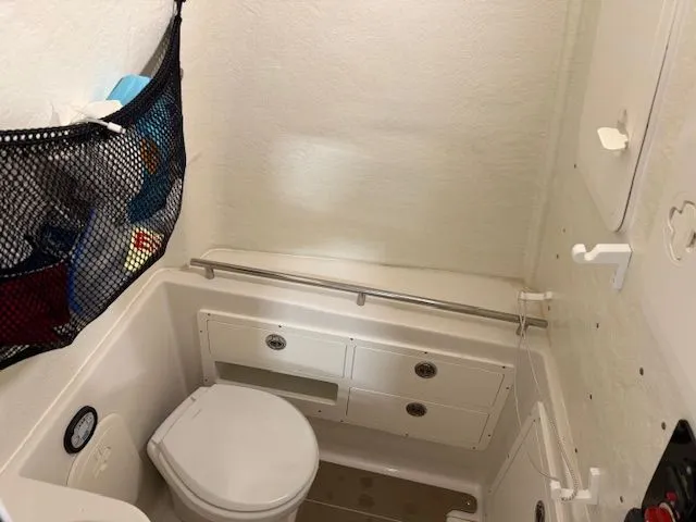 Slide: The Image of Compact bathroom in 2022 Sailfish 290cc boat, featuring toilet, storage, and netted organizer. - 18