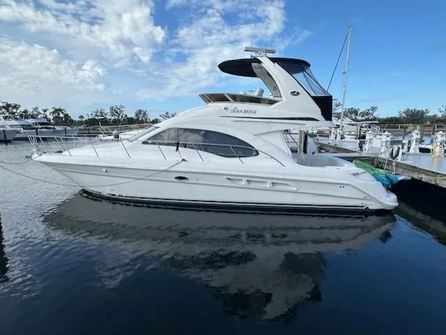 Slide: The Image of 2006 Sea Ray 44 Sedan Bridge yacht docked in a marina under a blue sky. - 2