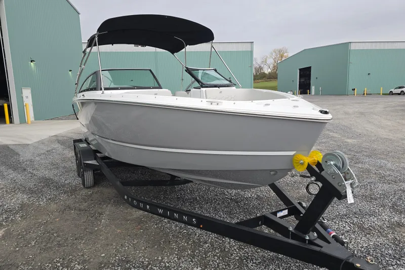 The Image of 2025 Four Winns H4 Freedom boat on trailer, parked outside green warehouses. - 0