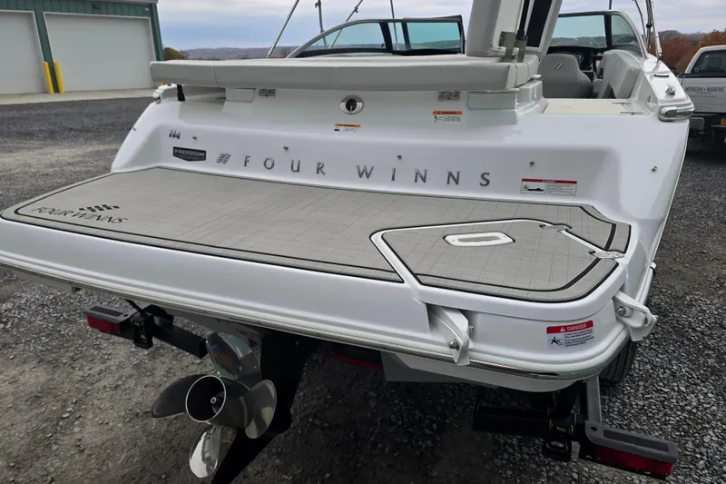 Slide: The Image of 2025 Four Winns H4 Freedom boat bow storage compartment with white cushioned seating. - 12
