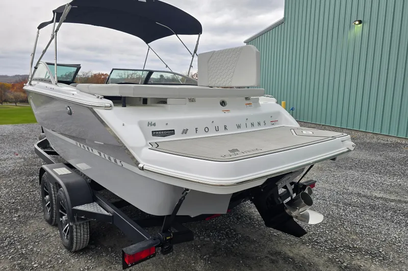 Slide: The Image of 2025 Four Winns H4 Freedom boat interior with white seating and cup holders. - 13