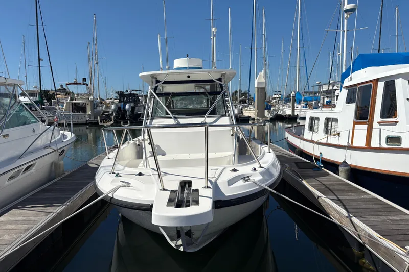 The Image of 2003 Boston Whaler 290 Outrage docked at marina with sailboats in background. - 1