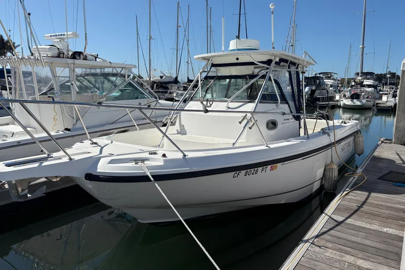 Slide: The Image of 2003 Boston Whaler 290 Outrage boat docked in a marina under clear blue skies. - 11