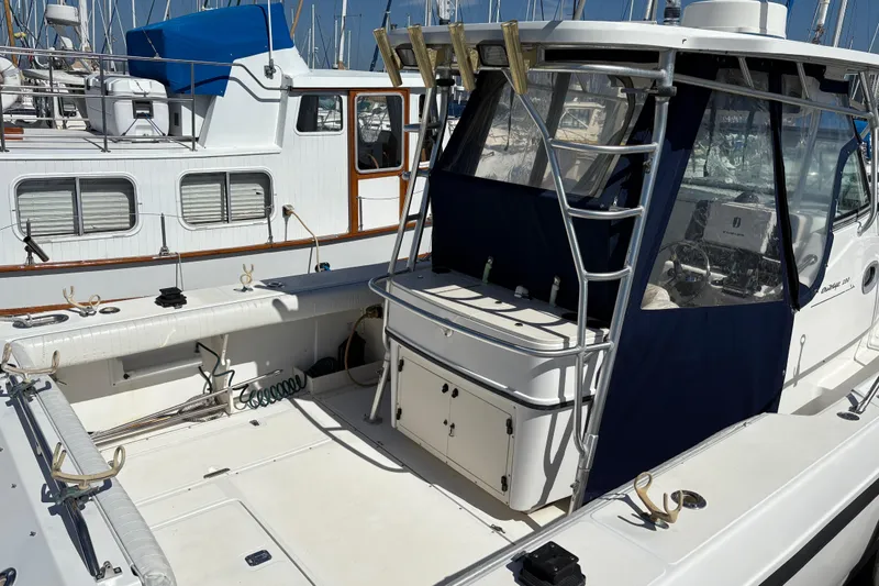 Slide: The Image of 2003 Boston Whaler 290 Outrage boat docked, featuring spacious deck and fishing equipment. - 4