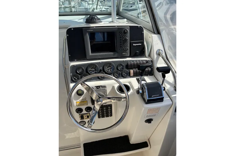 Slide: The Image of 2003 Boston Whaler 290 Outrage helm with steering wheel and navigation controls. - 6