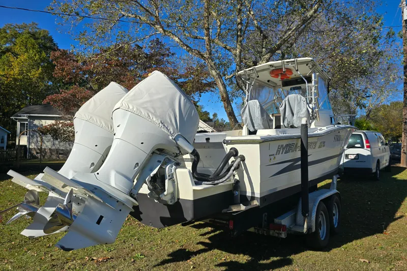 Slide: The Image of 1990 Hydra-Sports 2500WA boat on trailer with dual outboard motors, parked outdoors. - 3