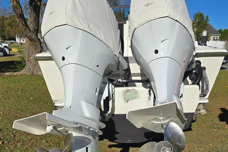 Slide: The Image of 1990 Hydra-Sports 2500WA boat with dual outboard motors, covered and parked on grass. - 5