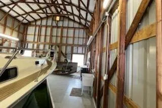 Slide: The Image of 1980 Custom Boathouse interior with wooden beams and docked boat. - 10