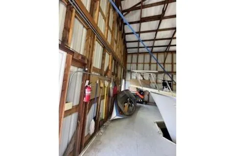Slide: The Image of 1980 custom boathouse interior with wooden beams and stored boat equipment. - 7