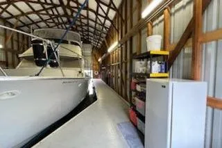 Slide: The Image of 1980 Custom Boathouse interior with docked boat and storage shelves. - 8