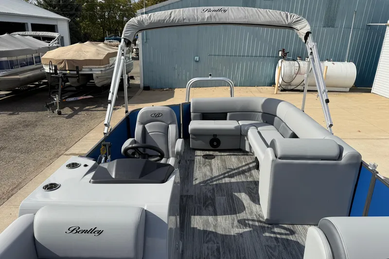 Slide: The Image of 2026 Bentley Pontoons Legacy 223 Cruise XL with gray seating and canopy, docked outdoors. - 15