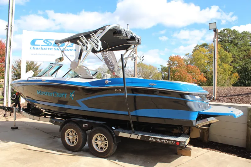 Slide: The Image of 2016 MasterCraft X30 boat on trailer, blue and black design, outdoor display. - 3