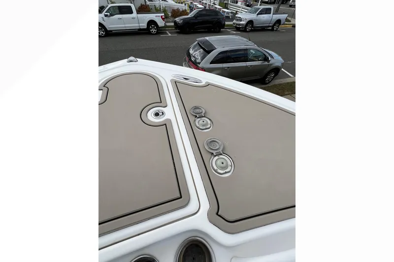 Slide: The Image of 2016 Tidewater 280 CC Adventure boat deck with hatches and fittings, parked cars in background. - 8