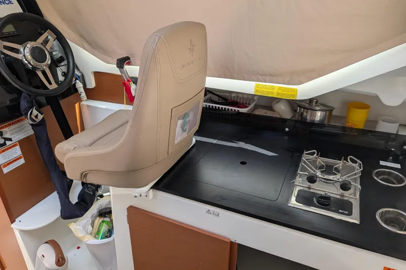 Slide: The Image of Interior of 2016 Jeanneau Merry Fisher 795 with helm seat and compact kitchen area. - 7