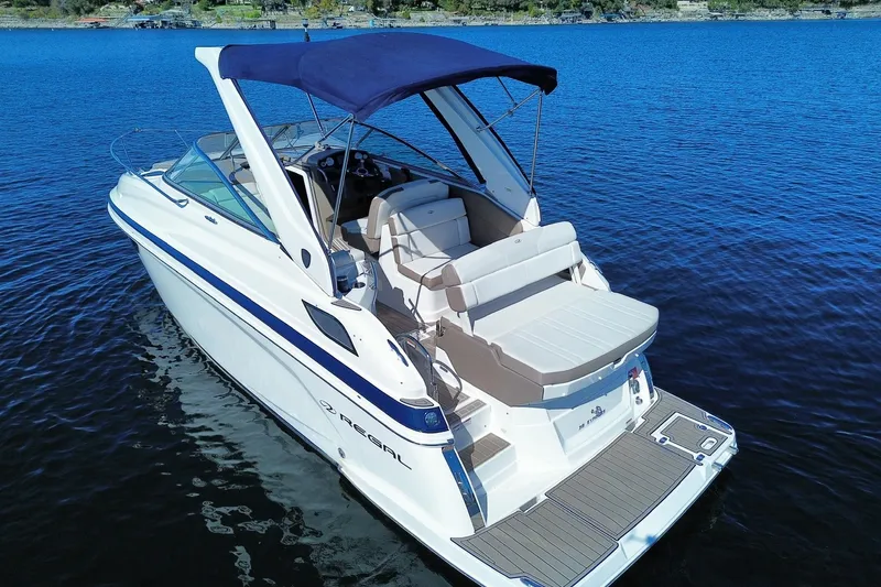 Slide: The Image of 2017 Regal 28 Express boat with blue canopy on calm water. - 1