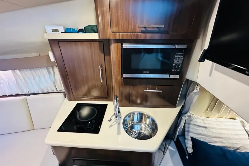 Slide: The Image of Compact kitchen area in a 2017 Regal 28 Express boat with microwave and sink. - 26
