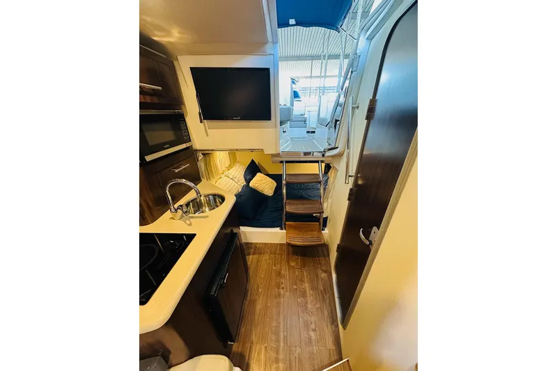 Slide: The Image of 2017 Regal 28 Express cabin interior with kitchenette, TV, and cozy seating area. - 28