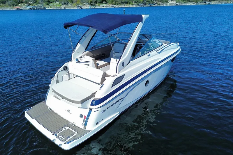 Slide: The Image of 2017 Regal 28 Express boat with blue canopy on calm water. - 3