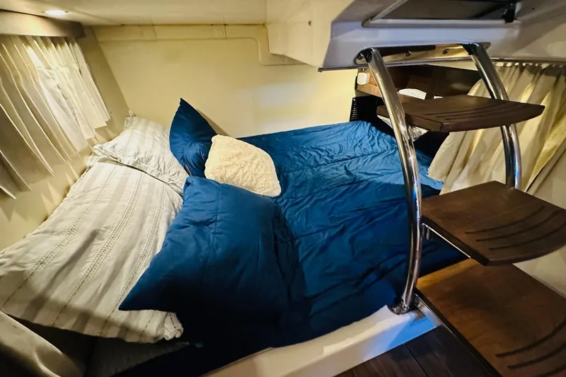 Slide: The Image of Cozy cabin interior of 2017 Regal 28 Express with blue bedding and wooden steps. - 31