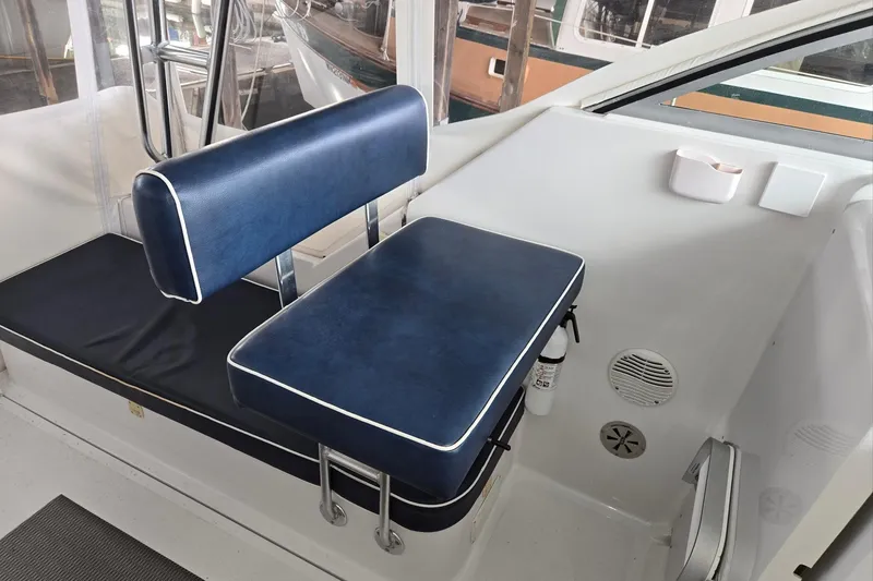 Slide: The Image of 1998 Mainship Pilot 30 interior with blue cushioned seating and white accents. - 18